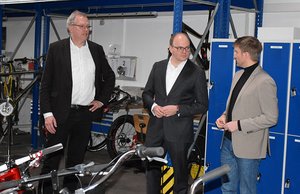 Dr. Martin Holler erläutert Alexander Föhr und Dr. Albrecht Schütte (von rechts) in der Fahrradwerkstatt das Ausbildungskonzept am BBW.